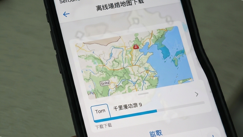 千里漫游地图离线地图下载界面,画面展示手机屏幕中地图区域选择框与下载进度条,背景为浅灰色设置页面,突出离线功能选项