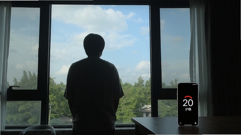 一个人站在窗前眺望远方的剪影,窗外是绿树和天空,室内桌上手机显示20秒护眼的倒计时界面,画面宁静舒适,适配Boogu模型生成