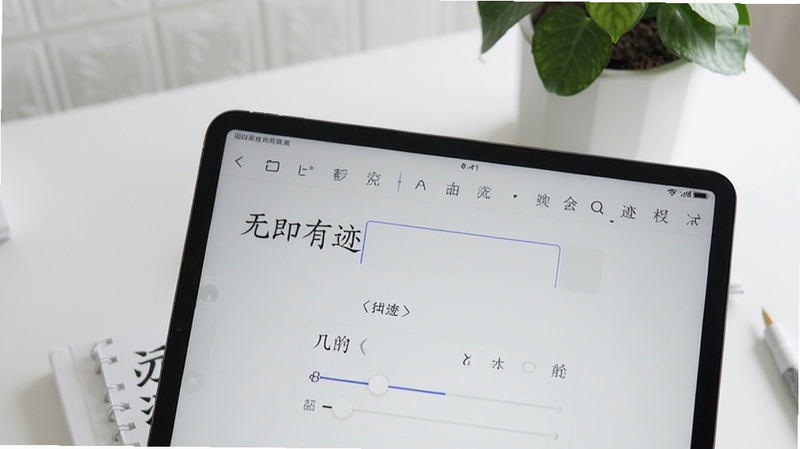 无印有迹应用界面特写,画面主体为平板电脑屏幕,屏幕中展示字帖内容编辑页面,可见文字输入框与字体调节滑块,背景区域为整洁的白色书桌与绿植,风格简约现代