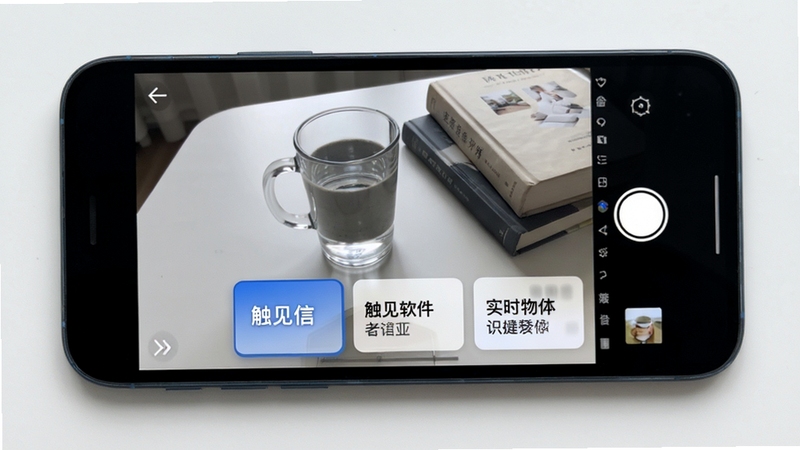 触见软件实时物体识别界面展示,手机摄像头对准桌面上的水杯与书籍,屏幕下方浮现识别标签卡片,界面简洁清爽,浅色背景,科技感蓝色点缀,俯视视角展示手机屏幕内容