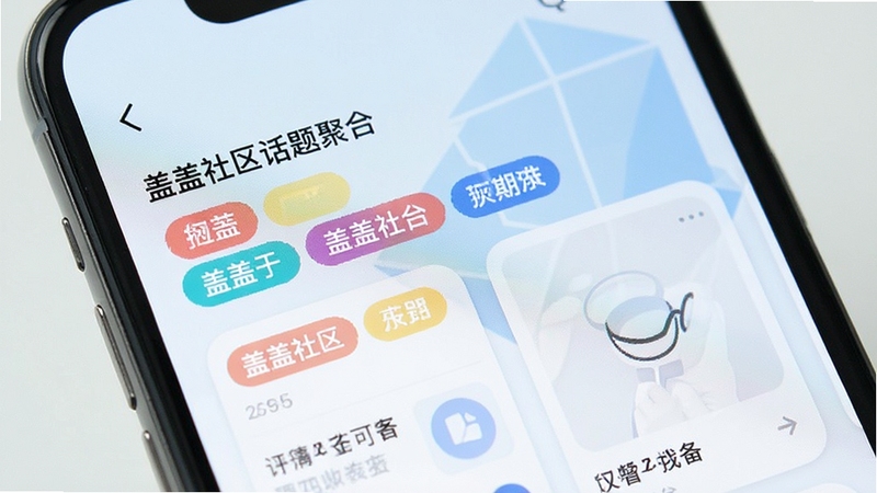 手机屏幕特写,显示盖盖社区话题聚合页面,彩色标签分类清晰,卡片式布局排列整齐,背景为淡蓝色抽象几何图形,风格简洁明快