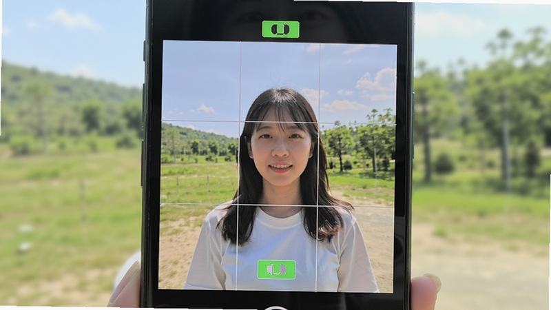 简单拍智能拍摄辅助功能展示,手机取景画面中带有九宫格构图线与水平仪标识,人物站在画面中央,背景为户外自然光场景,画面干净明亮,体现简单拍的拍摄辅助能力