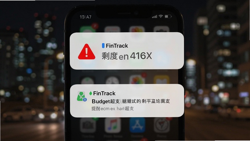 手机界面弹出 FinTrack 预算超支提醒通知,屏幕上方显示红色预警图标与剩余额度数字,背景为虚化的城市夜景,画面氛围略带紧张感,突出提醒功能