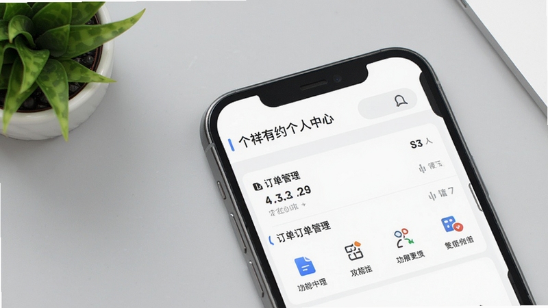 吉祥有约个人中心页面细节图,画面主体为手机界面局部放大,显示订单管理列表与功能图标排列,背景为纯色浅灰工作台面,搭配少量绿植点缀,风格干净利落,适合功能说明配图