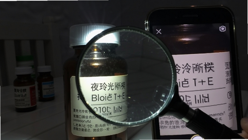 玲珑放大镜夜间补光模式演示,手机闪光灯照亮药瓶标签,屏幕显示清晰放大文字,背景为昏暗房间