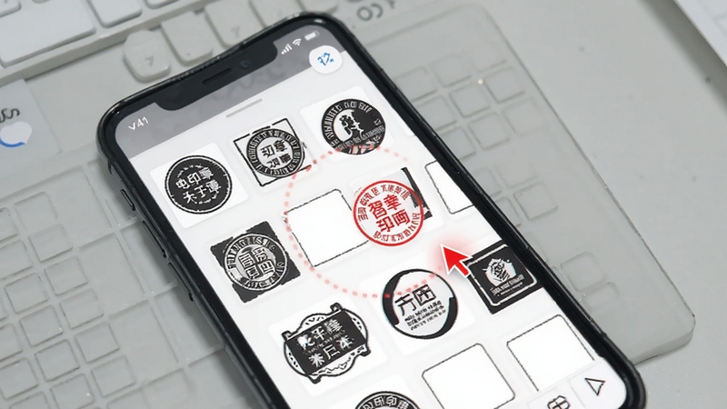 电子印章生成工具模板选择界面,手机屏幕显示多个圆形与方形印章模板缩略图排列整齐,背景为淡灰色工作台面,画面中带有红色印章预览与编辑光标元素,整体色调清爽,适合软件功能介绍配图