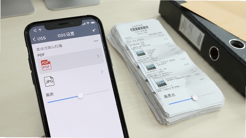 手机屏幕显示OSS文档扫描的导出设置面板,列表中可见PDF、JPG格式选项与画质滑块,背景为浅色办公桌面,旁边放置一叠整理好的纸质票据与一个文件夹,画面风格简洁明亮,突出文件导出的操作细节