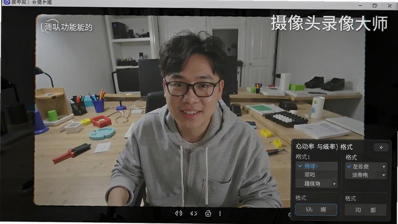 摄像头录像大师高清录制功能展示图,画面中显示摄像头捕捉的清晰人物画面,右下角有分辨率与格式选择菜单,背景为工作台场景,软件名称以水印形式呈现