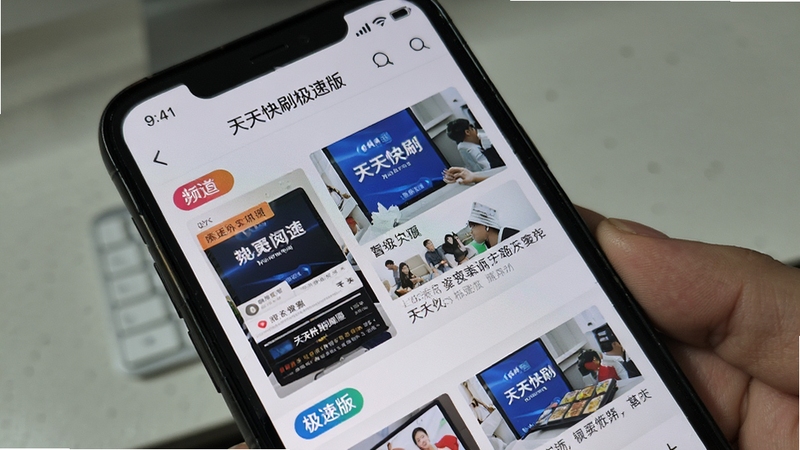 展示天天快刷极速版资讯阅读界面,手机屏幕上呈现图文并茂的新闻列表,配以鲜明的频道标签,背景采用浅灰色调,模拟真实使用环境,画面主体为手机屏幕特写,细节清晰,强调资讯丰富性与界面简洁性