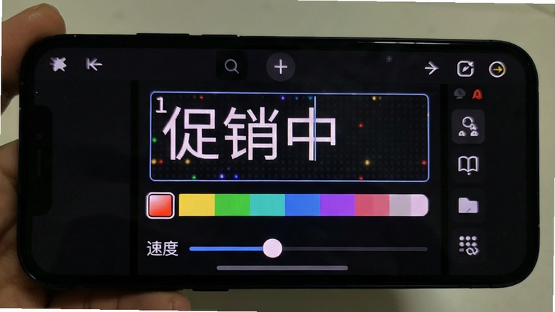 手机屏幕显示LED字幕软件编辑界面,文字输入框内写着“促销中”,下方有颜色选择条和速度滑块,背景为深色UI,突出LED字幕生成器操作界面细节
