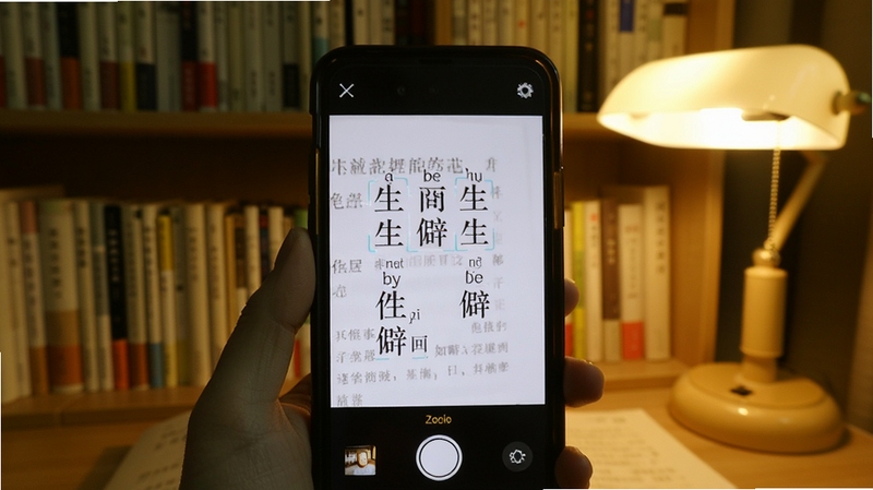 拍照查 文字识别界面 手机拍摄书本上的生僻字 屏幕上显示拼音和释义 背景是书架和阅读灯 氛围安静