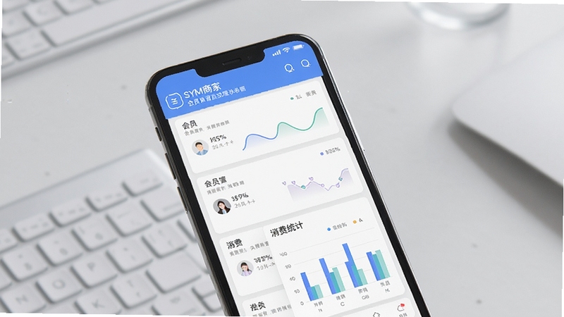 SYM商家 会员管理模块界面图,画面展示手机屏幕上的会员列表与消费统计图表,背景为柔和的浅灰色办公桌面,风格清新简洁,突出数据可视化效果