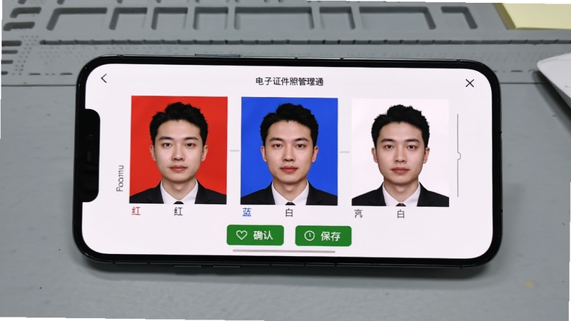电子证件照管理通一键换底功能演示,手机屏幕展示同一张人像照片在红、蓝、白三种背景色之间切换,界面带有确认与保存按钮,背景为简洁的灰色工作台,适配Boogu模型生成