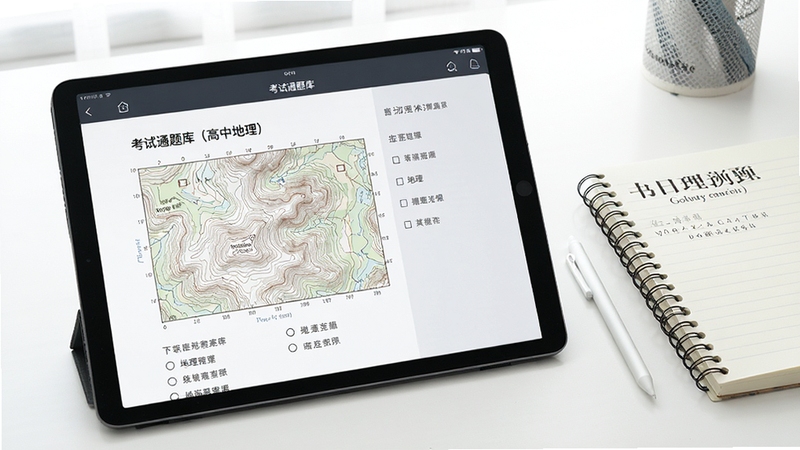考试通题库(高中地理)在平板电脑上的使用场景展示,画面中一台平板电脑横屏显示地理试卷练习界面,屏幕上呈现等高线地形图题目和选项,旁边放着一支触控笔和一本地理笔记本,整体环境整洁明亮,适合展示移动端学习场景