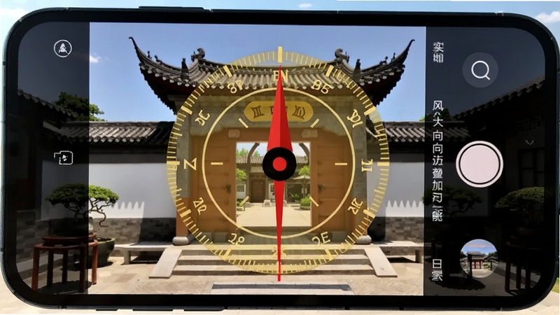 风水电子罗盘实景拍照定向叠加功能演示,画面主体为手机屏幕显示相机取景框,框内是一座中式庭院的大门,屏幕上叠加了半透明的金色罗盘刻度和红色的方向指示线,背景为晴朗的白天,画面构图工整,色彩对比鲜明。