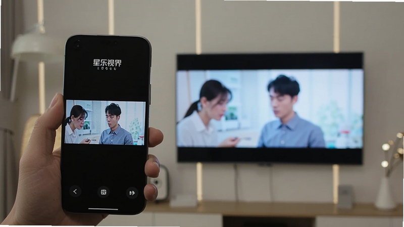 星乐视界 投屏功能展示 手机与电视屏幕同时显示相同视频画面 手机在手中 电视在背景墙上 画面明亮 星乐视界Logo出现在手机屏幕 适配Boogu模型